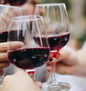 tre persone tengono in mano dei bicchieri di vino rosso