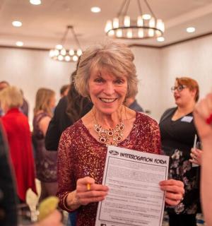 a woman holding a piece of paper in a crowd of people