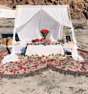 un pat cu flori și un baldachin alb pe plajă