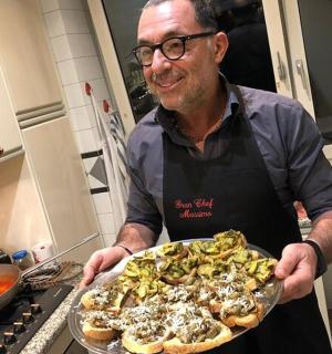 厨房里拿着一盘披萨的男人