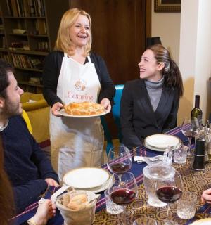 skupina lidí sedících kolem stolu se ženou držící talíř s jídlem