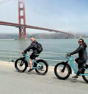 two people riding bikes in front of the golden gate bridge