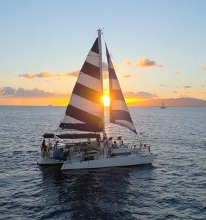 plachetnice na vodě se zapadajícím sluncem