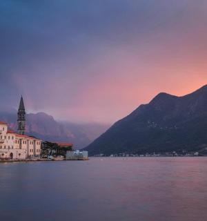 一座有钟楼和山脉的水上小镇