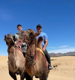 two men riding on the backs of camels in the desert