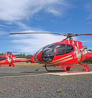 two red helicopters are parked on a runway