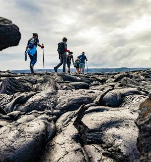 skupina tří lidí kráčejících po skalách
