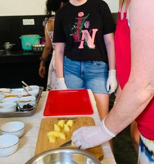 two people standing in a kitchen preparing food on a cutting board
