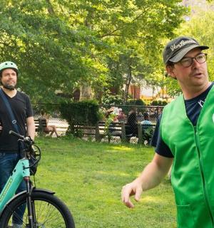 two men standing in a park with a bike
