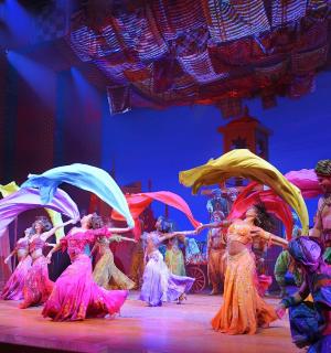a group of people dancing on a stage with umbrellas
