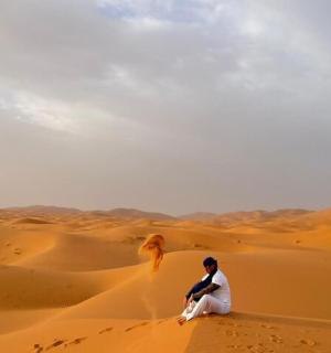 a man sitting on the sand in the desert