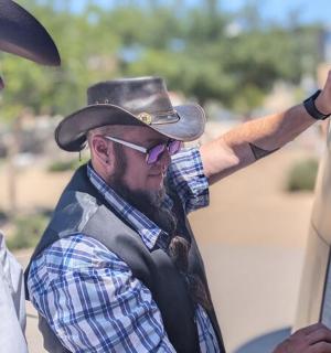 a man wearing a cowboy hat looking at a sign