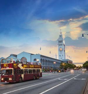 a double decker bus driving down a street with a clock tower
