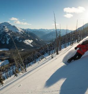 osoba jedoucí na snowboardu po zasněženém svahu