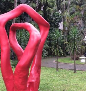 a large red sculpture of two swans in a park