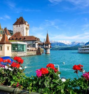 a cruise ship on a lake in front of a castle