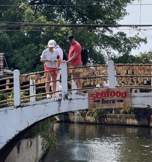 two people standing on a bridge over a river