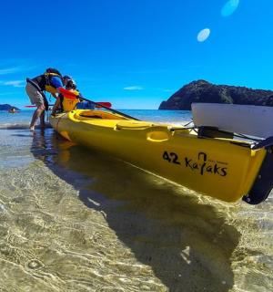 几个人站在海滩上的一艘黄色小船旁边