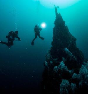 two people swimming in the ocean next to a rock formation