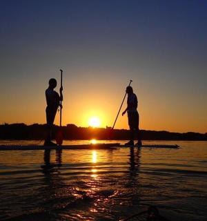 two people on a paddle board in the water at sunset