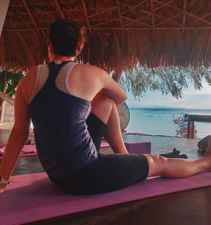 a woman sitting on a yoga mat looking at the ocean
