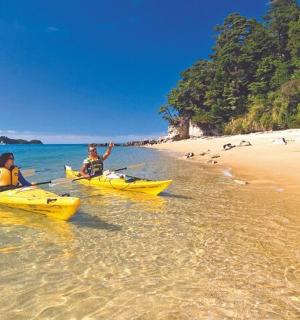 tři lidé v kajacích ve vodě na pláži