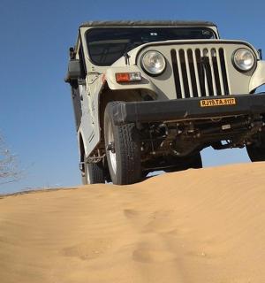 a jeep parked on top of a sand hill
