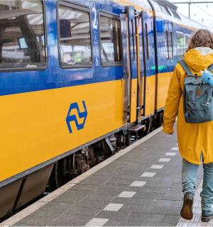 背着背包在火车旁边行走的人