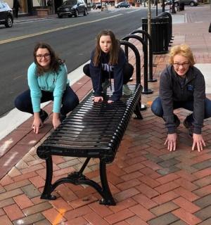 三个女孩坐在街边的长椅上