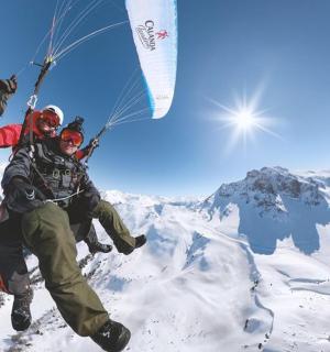 two men are flying a kite on top of a mountain