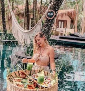 a woman standing in front of a basket of food next to a pool
