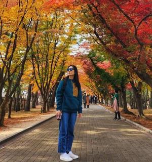 一位女士站在树木繁茂的公园小路上