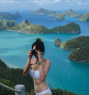 一位身穿比基尼的女子正在拍摄湖景