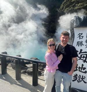 a man and woman standing in front of a steam train