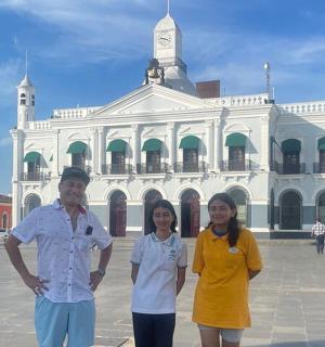 three people standing in front of a white building