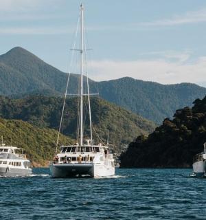 水中有三艘船，背景是群山