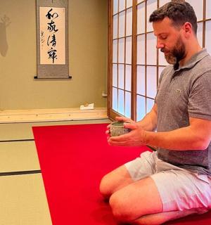 一位男士坐在红地毯上,手里拿着一个杯子