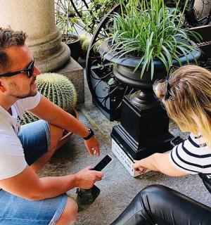 a man and woman sitting on a bench looking at a cell phone