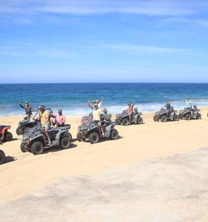 a group of people riding atvs on the beach