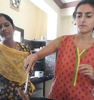 两个女人站在厨房里,手里拿着筷子