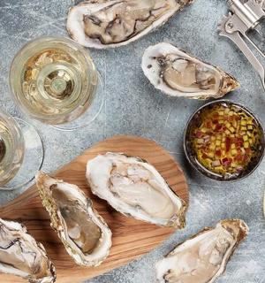 a table with a plate of oysters and glasses of wine