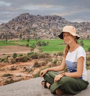 一位女士坐在岩石上，背景是一座山