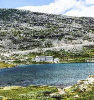 a house on the shore of a lake in front of a mountain