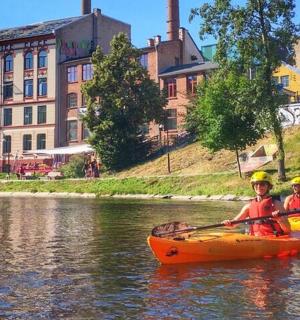 两个人在河边划皮划艇,河上有一座建筑