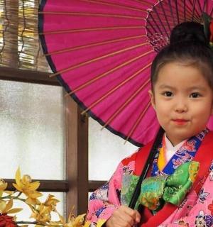 a young girl in a kimono holding a pink umbrella