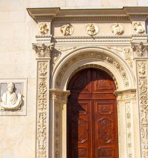 an arch over a door with two statues above it