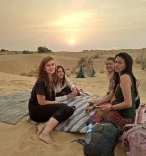 skupina žen sedících na dece v písku