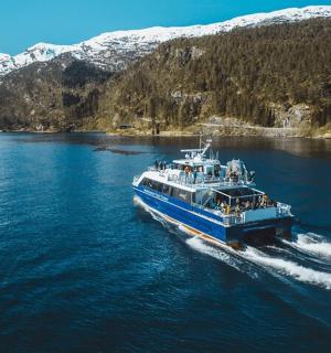 a ferry boat on a river with snow covered mountains
