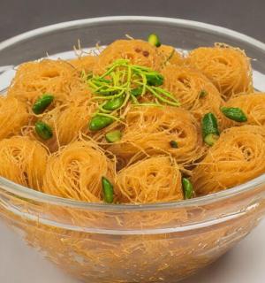 a glass bowl filled with noodles and green onions