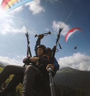 two people are sitting on a hill flying a kite